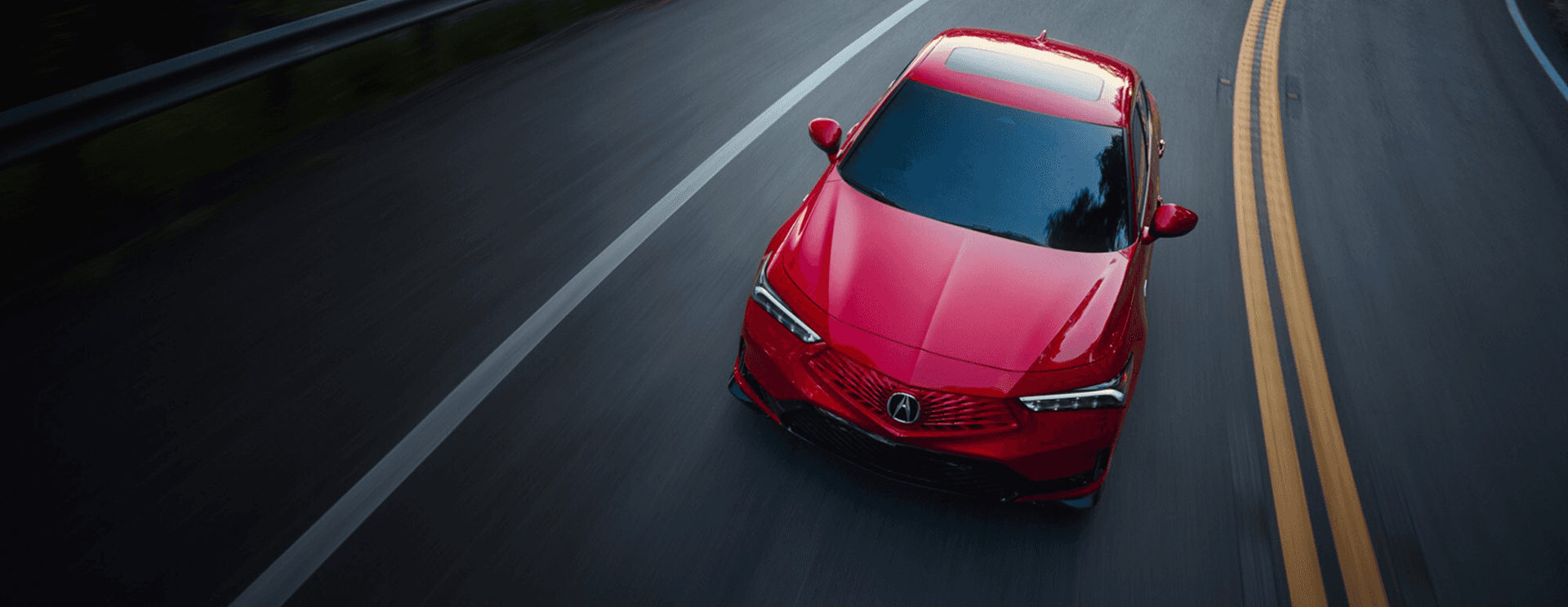 2026 Acura Integra A-Spec in Performance Red Pearl driving on a scenic road