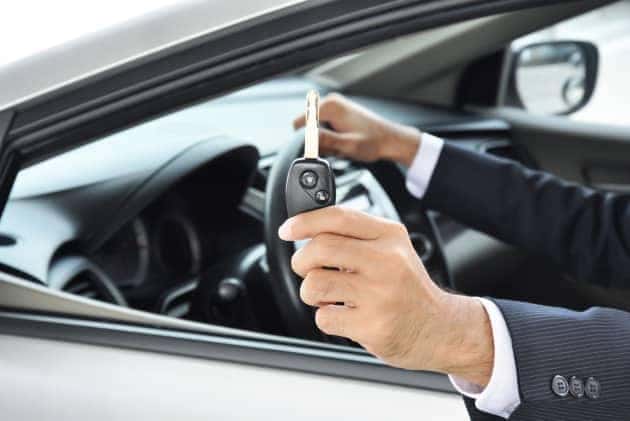 View of a person sitting in their car handing over the keys to the vehicle