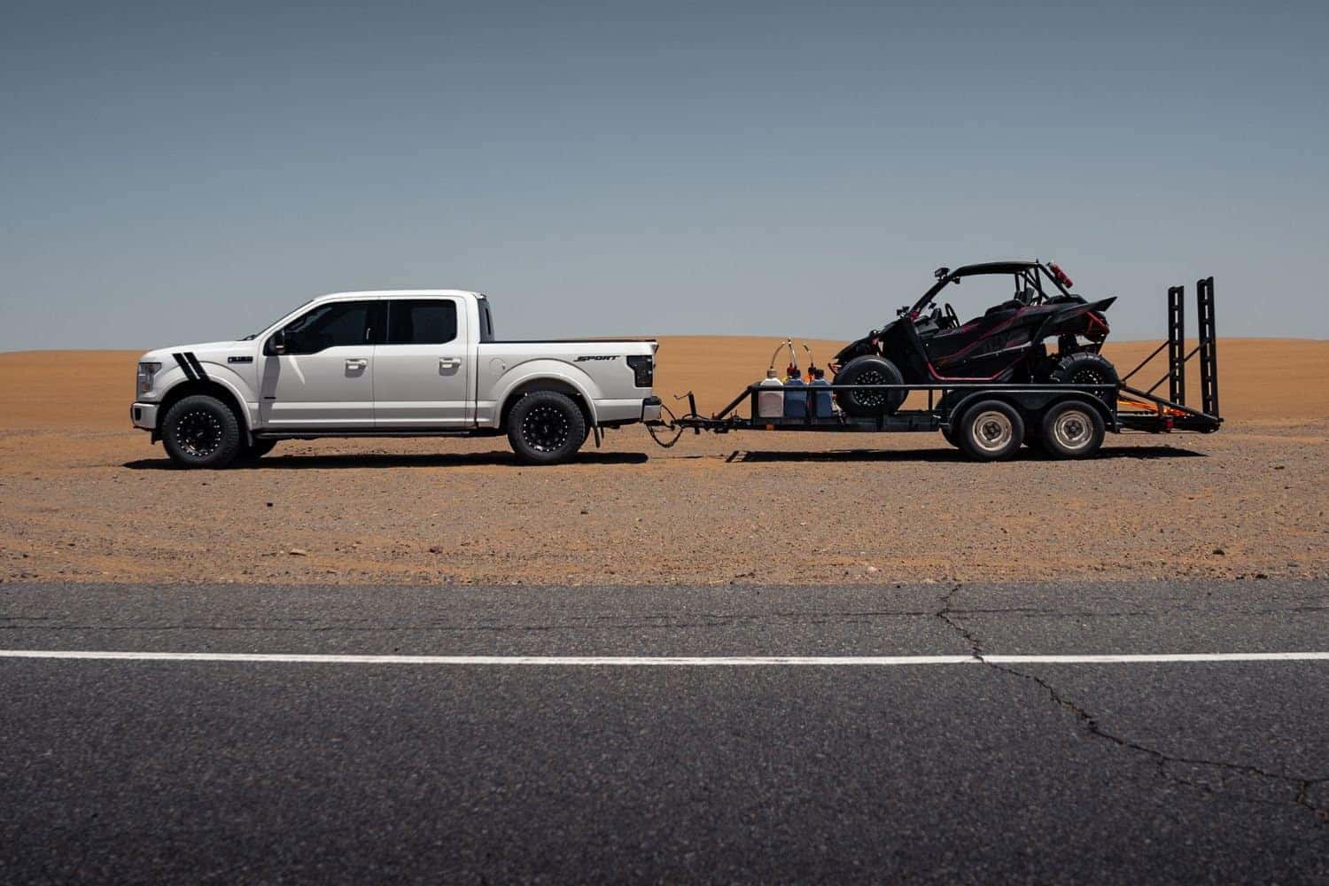 A White Truck Towing A Trailer, In The Middle Of A Desert