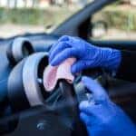A Car Owner Wiping Their Grimy Steering Wheel To Clean Their Car Interior