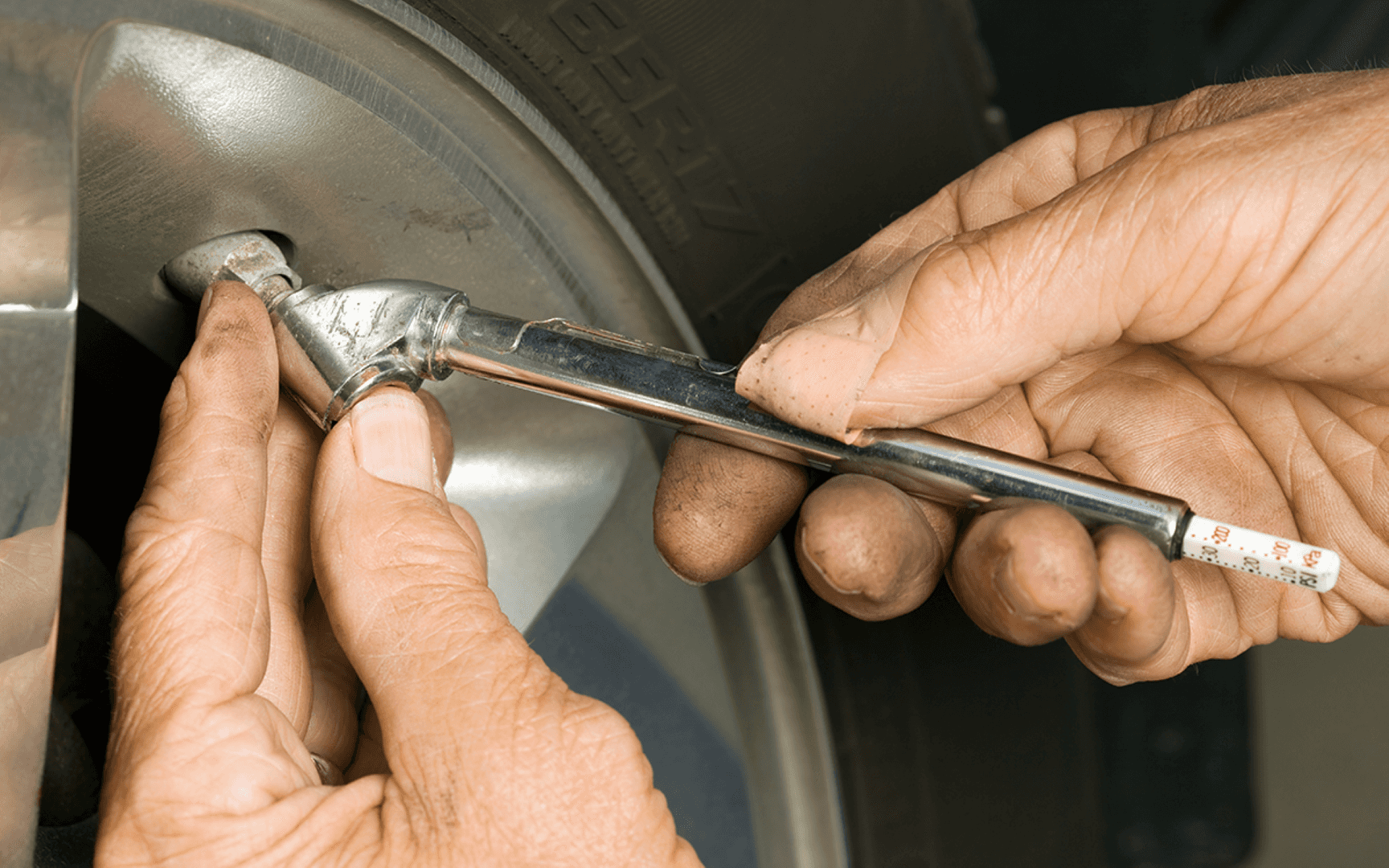 An Automotive Worker Checking The Tire Pressure With A Tire Pressure Guage