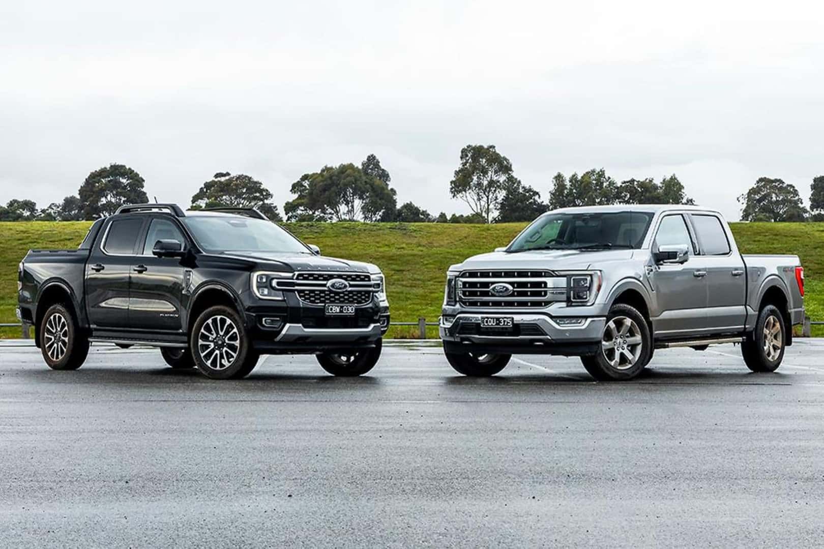 The Notable And Star 2024 Ford Ranger Duo Parked In A Rained-In Parking Lot, Near A Mound Of Dirt And Grass, With Outstanding Trees In The Distance