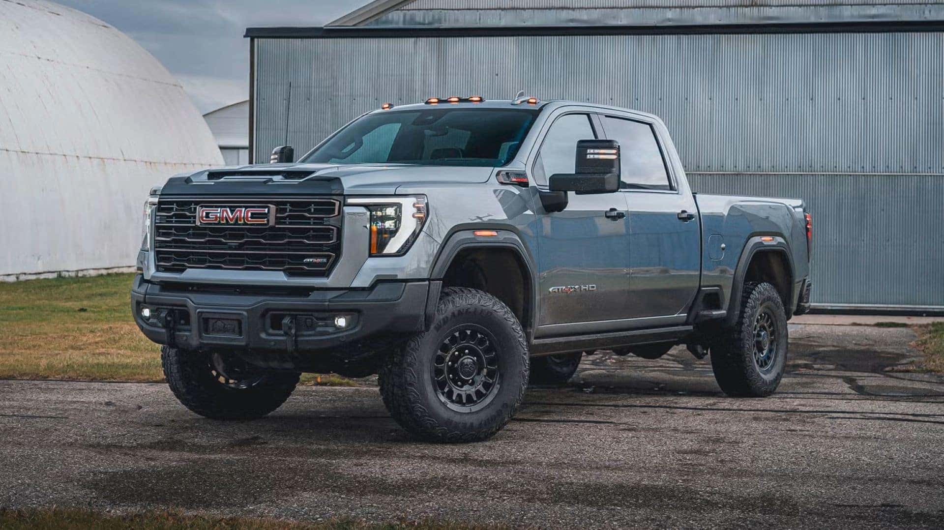 The 2024 GMC Sierra 2500HD AT4X, With Great Towing Capacity, Parked Outside A Metallic Building