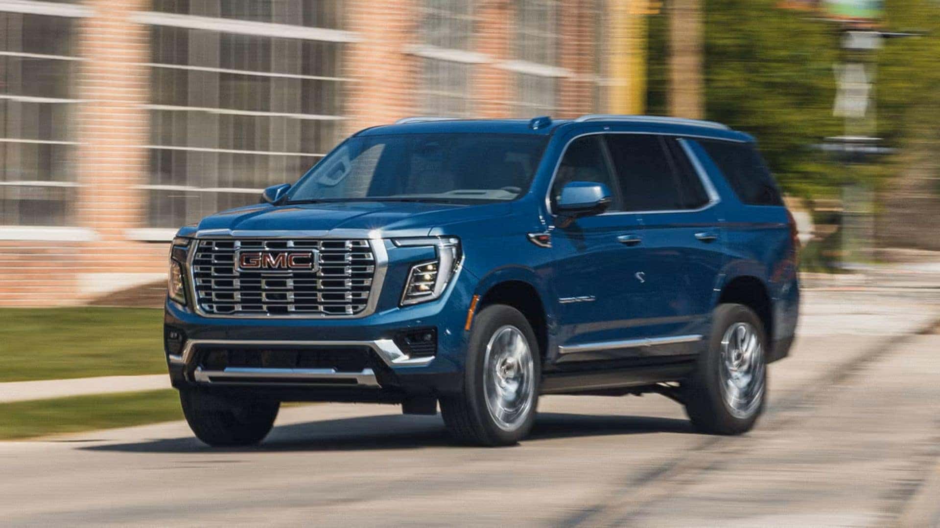 The Sparkling And Comfortable 2025 GMC Yukon, Driving Past A Windowed Building