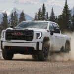 The Off-Road Master, 2026 GMC Sierra 2500, Driving Off Dust As It Speeds Away From Tall Pine Trees