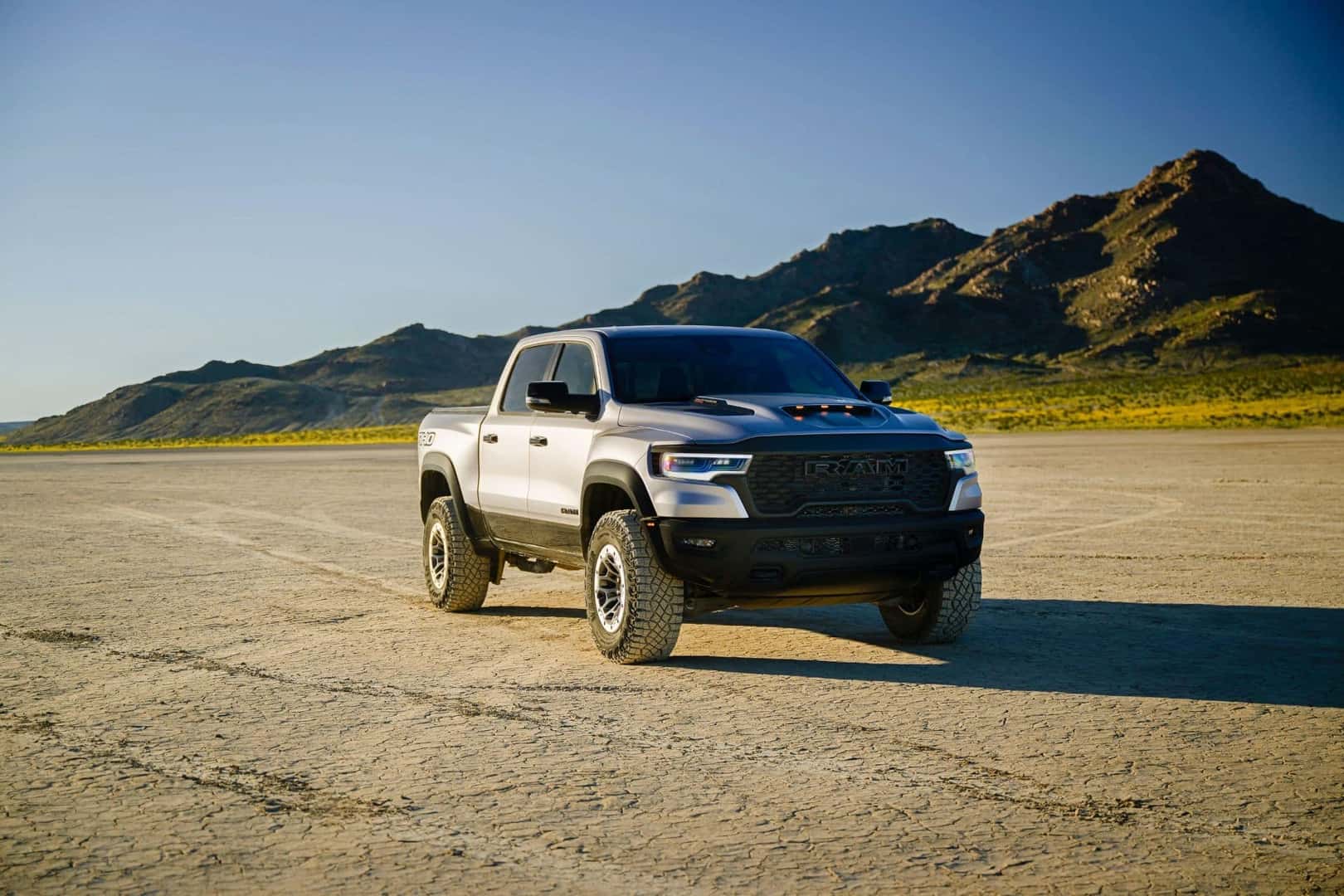 The Proficient Ram 1500, Driving On A Super Flat Field, With Ridged Mountains In The Background
