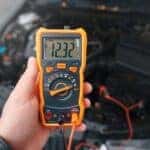 A Driver Using A Voltmeter To Check Their Car's Charge, Maintaining Maintenance