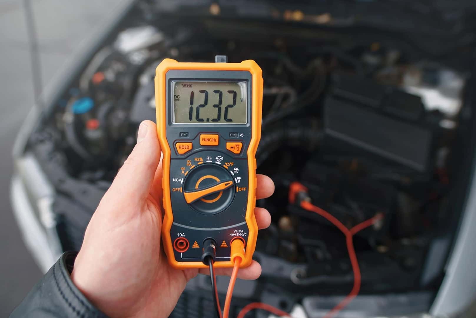 A Driver Using A Voltmeter To Check Their Car's Charge, Maintaining Maintenance