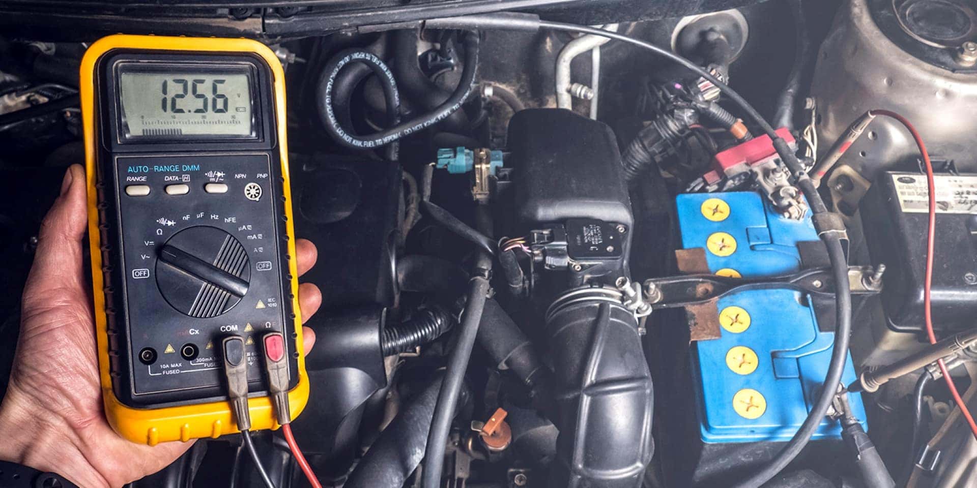 A Driver Using A Multimeter To Test Their Car Battery