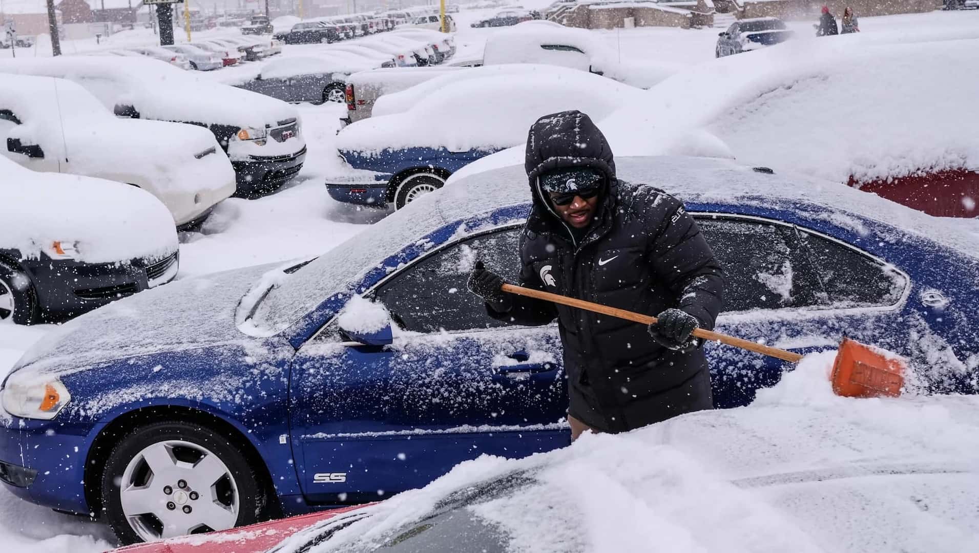 Man Shoveling Snow from Blue Car