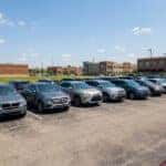 Pre-owned SUVs and sedans on a used-car lot in Fishers, Indiana on a sunny August day