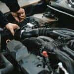 An Auto Mechanic Checking the Engine of a Car