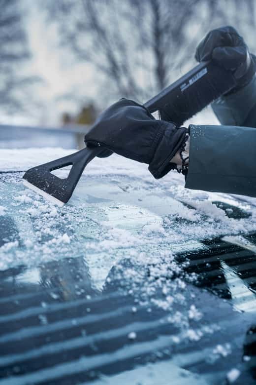 Person scraping ice off of a windshield