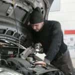 Man in Black Jacket and Black Knit Cap Inspecting Car Engine
