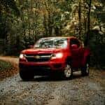 a red truck is driving down a dirt road