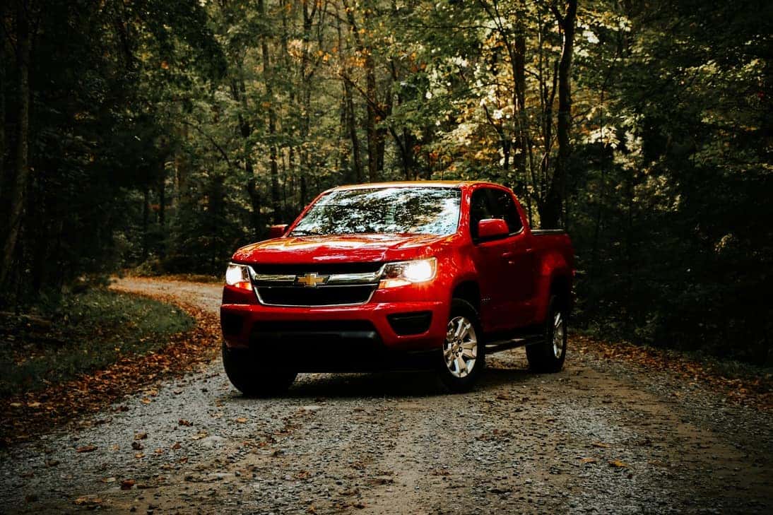 Red Chevy truck driving down a dirt road