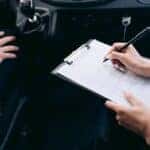 Person Writing on a Clipboard Inside the Vehicle
