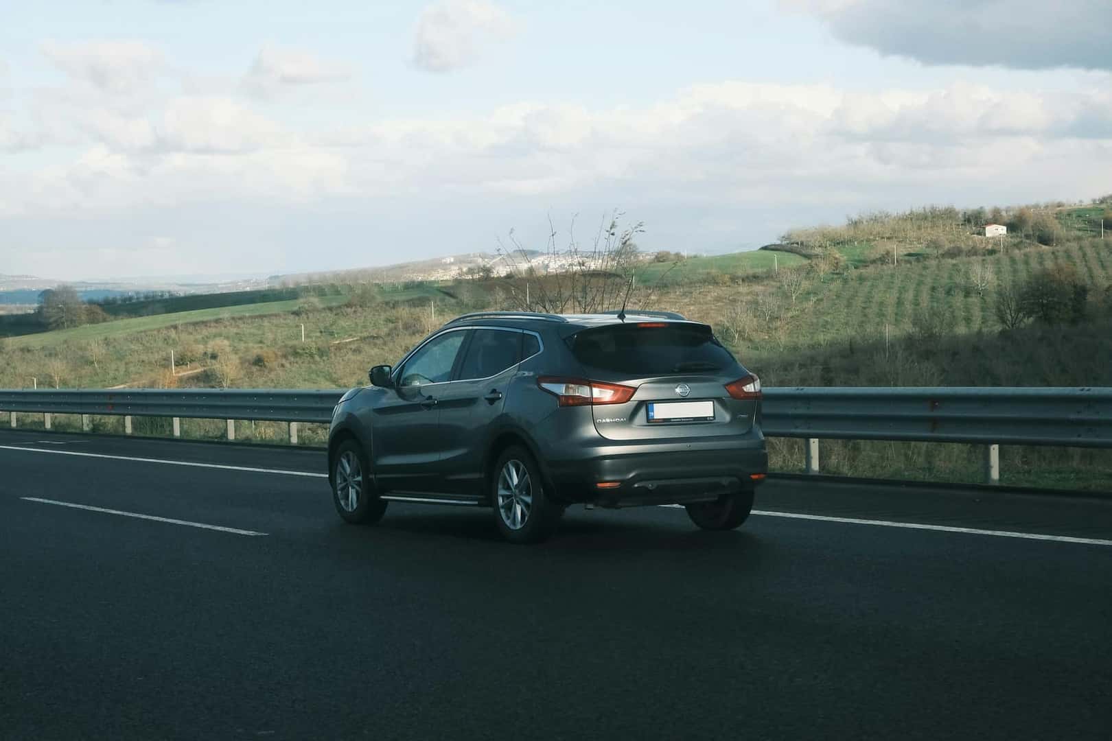 car driving down a highway next to a lush green hillside