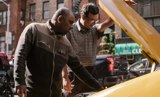 Multiethnic men repairing car on street