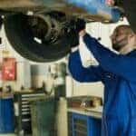 Man in Blue Work Clothes Fixing a Car