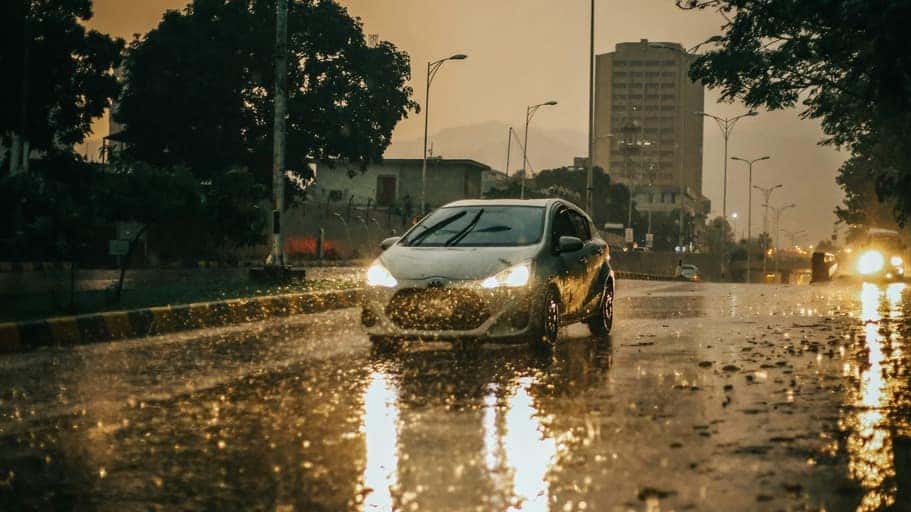 A car driving down a rain-soaked street