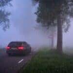 a car driving down a road in the fog
