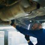 Man in Blue Coverall Checking Under A Vehicle