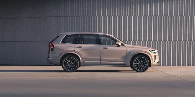 A profile view of a silver Volvo XC90 parked in front of a building.