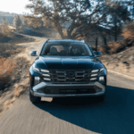 Bold front profile of the 2025 Hyundai Tucson Hybrid driving through scenic Athens, GA roads, showcasing its eco-friendly performance.