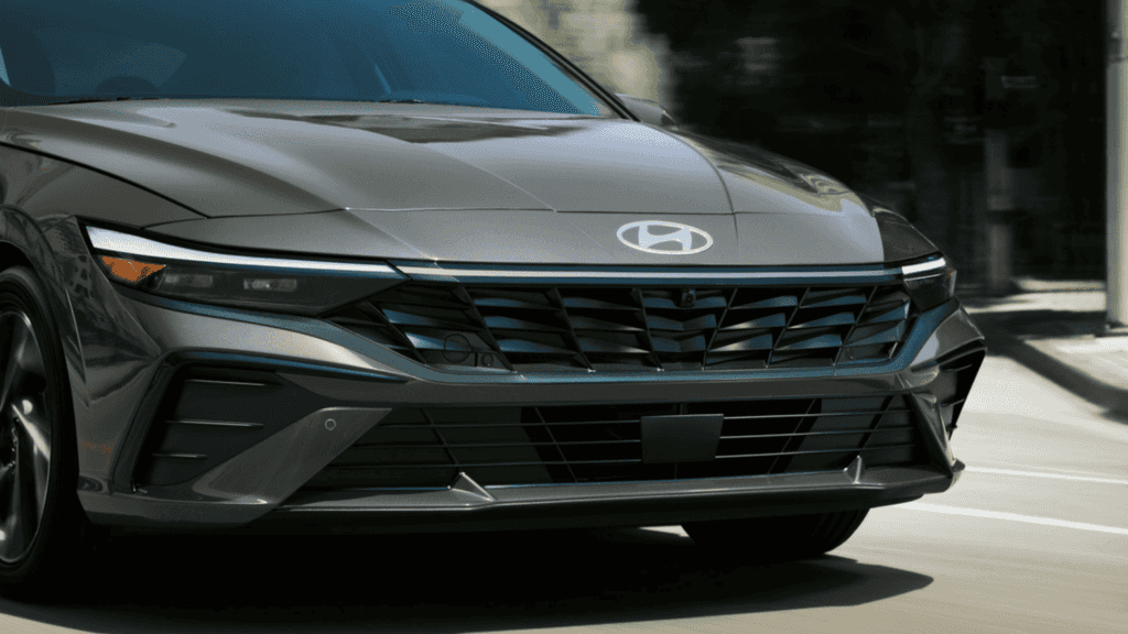 Front grille of the 2025 Hyundai Elantra Hybrid featuring a sharp LED headlight design and modern chrome accents