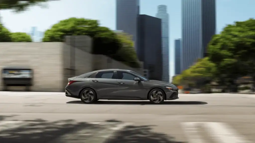 2025 Hyundai Elantra Hybrid driving through a modern cityscape with sleek design and fuel-efficient performance.