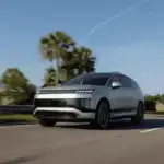 2026 Hyundai IONIQ 9 electric SUV driving past palm trees, highlighting futuristic styling and zero-emissions power.