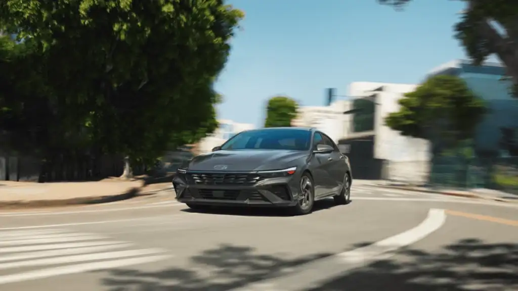 2025 Hyundai Elantra Hybrid in motion on a city street, displaying its aerodynamic design and fuel-efficient performance.