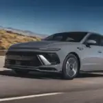 2025 Hyundai Sonata Hybrid driving through a desert highway, presenting its sleek silhouette and hybrid powertrain benefits.