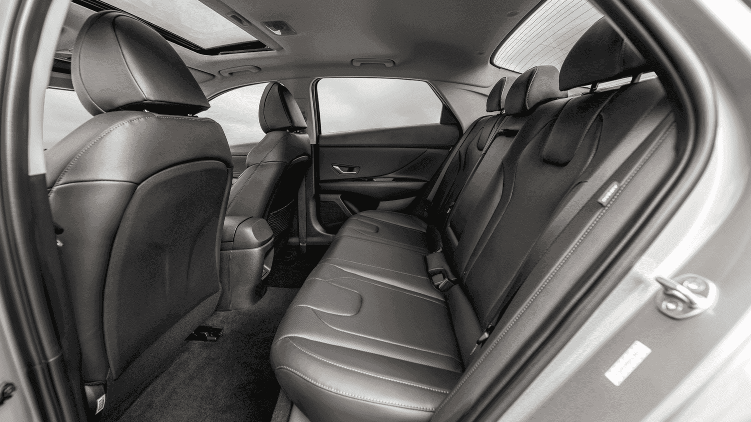 Spacious rear seating of the 2025 Hyundai Elantra, photographed in Athens, GA, featuring black leather seats and a panoramic sunroof for premium passenger comfort.