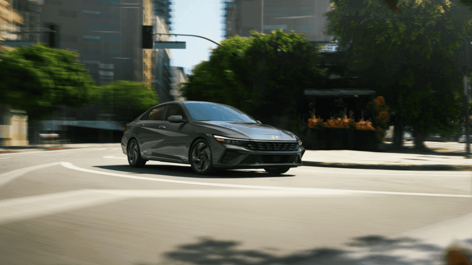 Sleek gray 2025 Hyundai Elantra Hybrid navigating city streets, perfect for urban life in Athens, GA.
