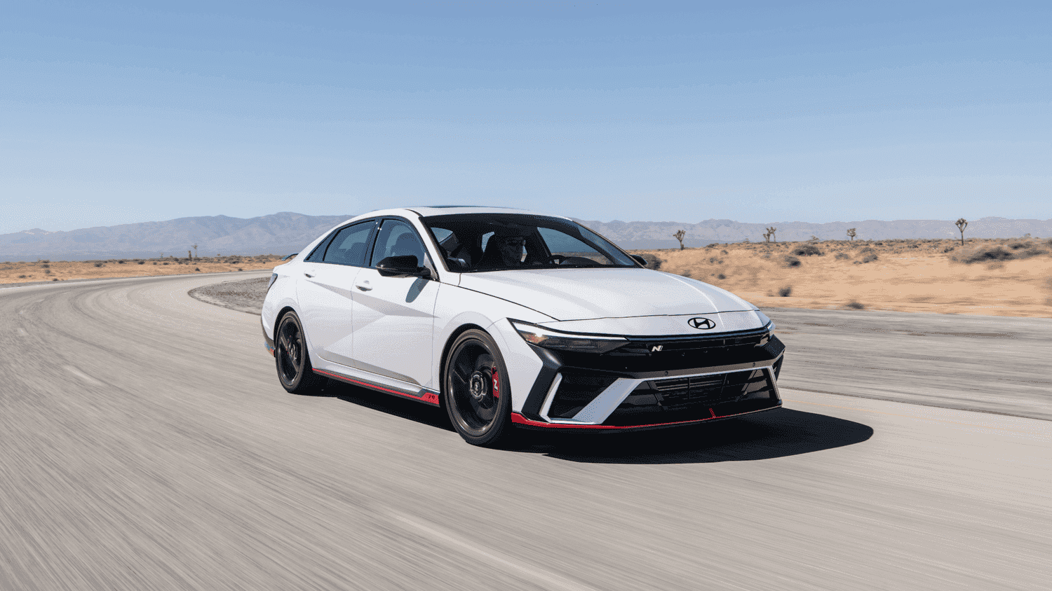 White 2025 Hyundai Elantra N taking a corner on a race track—high-performance thrills ready for Athens, GA drivers.