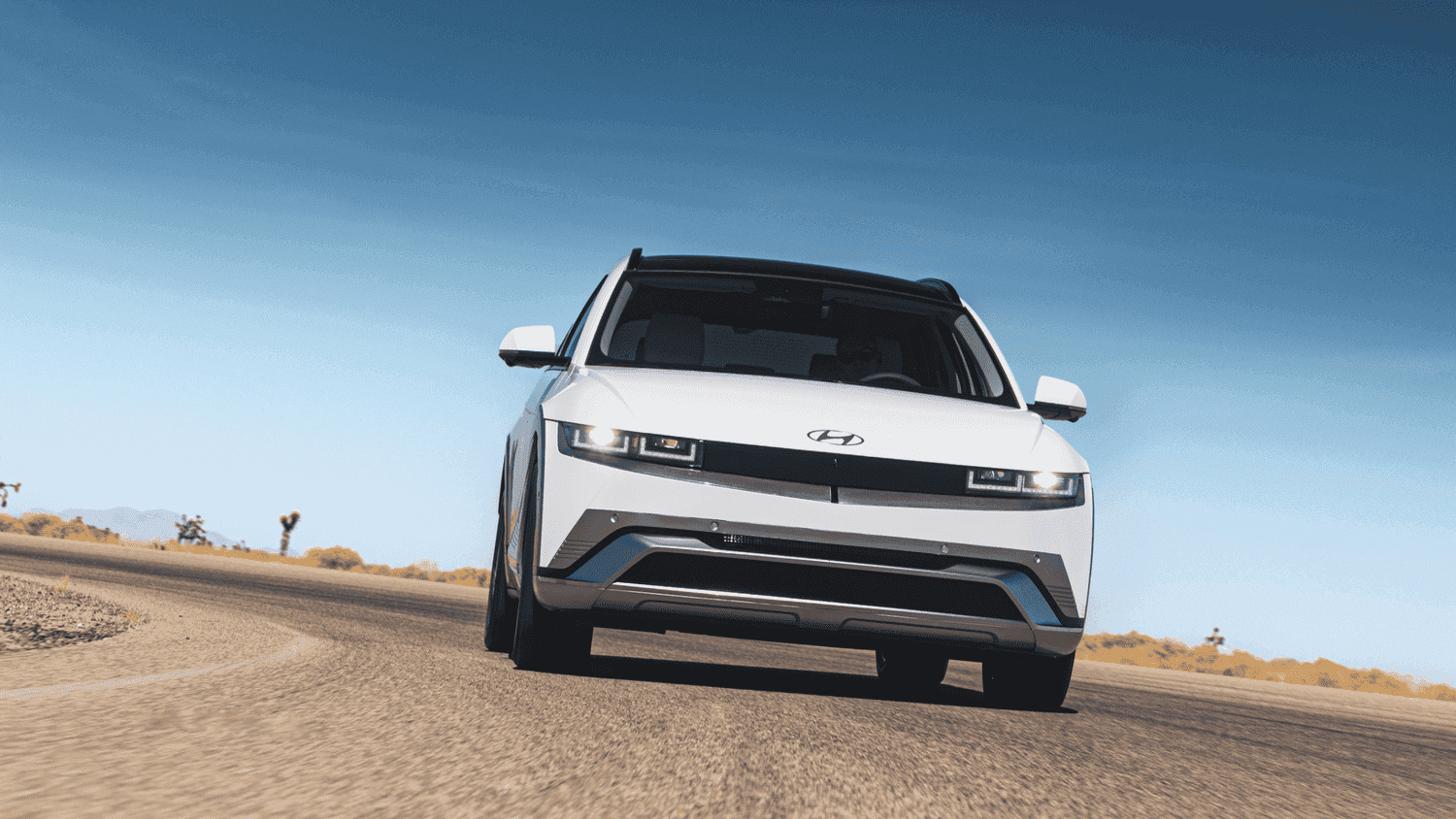 2025 Hyundai IONIQ 5 driving on a desert highway near Loganville, GA, emphasizing its bold EV styling and wide stance.