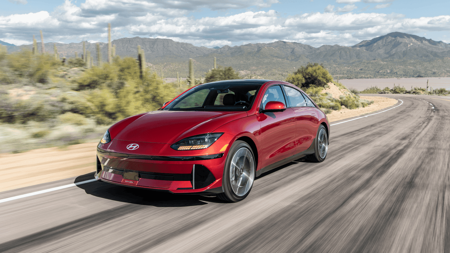 2025 Hyundai IONIQ 6 in red driving along a scenic road, illustrating aerodynamic design and electric performance near Athens, GA.
