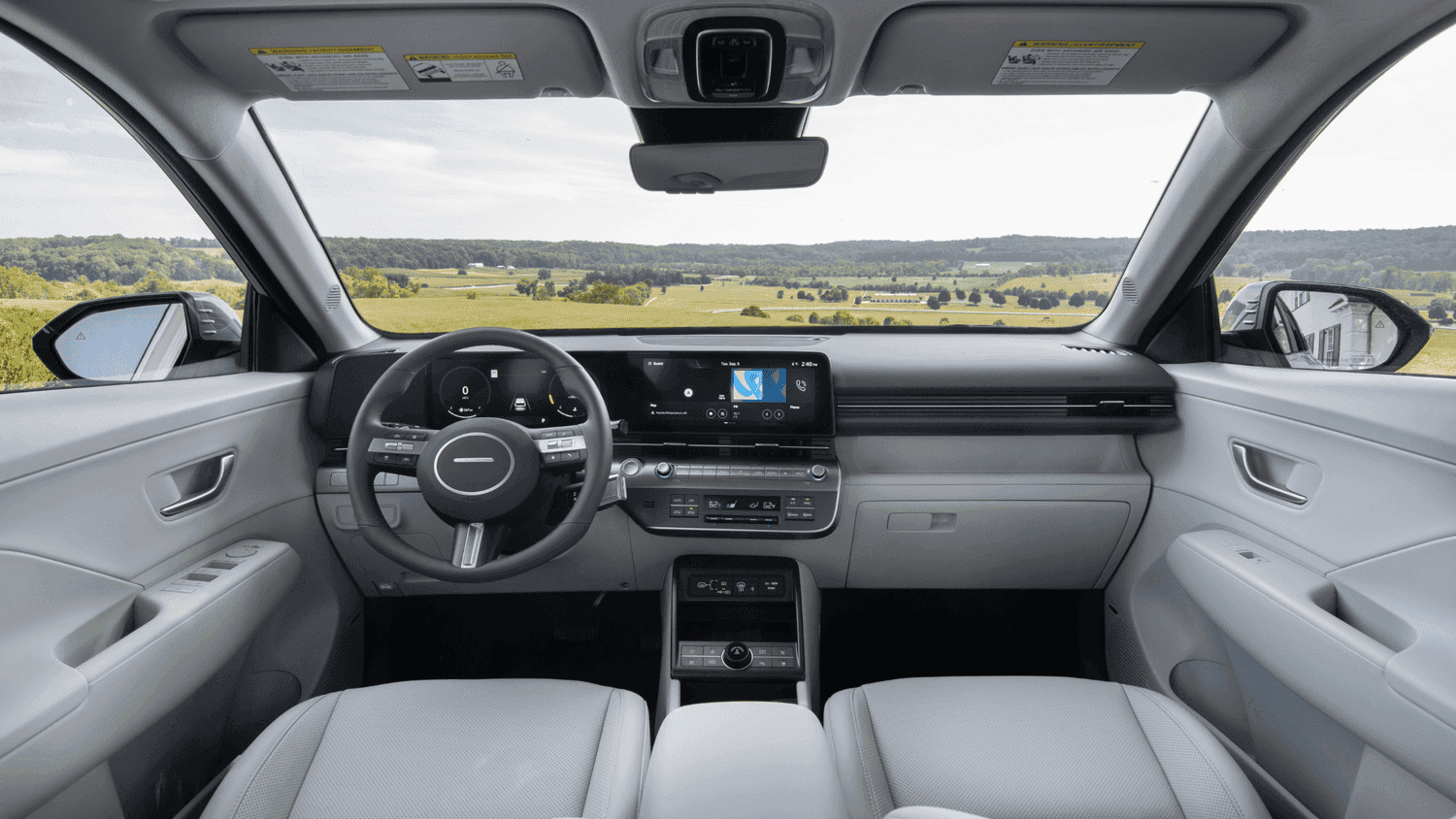 Driver-focused interior of the 2025 Hyundai Kona in Athens, GA, showcasing a digital instrument cluster, touchscreen display, and light leather seating.