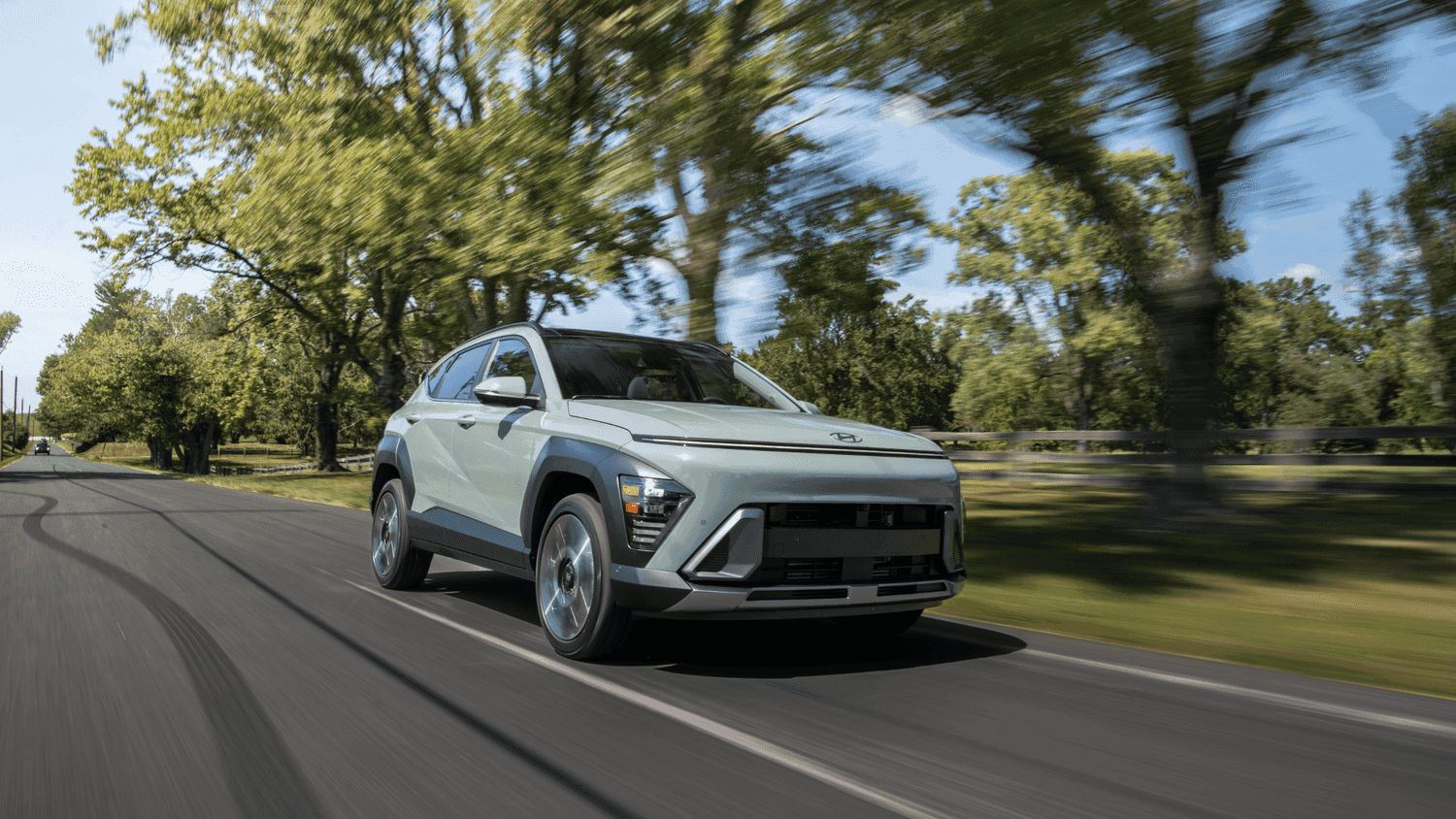 2025 Hyundai Kona in motion on a scenic road near Loganville, GA, highlighting its bold grille and compact SUV design.