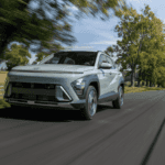 2025 Hyundai Kona compact SUV driving through tree-lined roads near Loganville, GA, designed with family-friendly features.