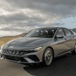 2025 Hyundai Elantra sedan driving on an open road near Loganville, GA, showcasing its sleek design and fuel-efficient performance.