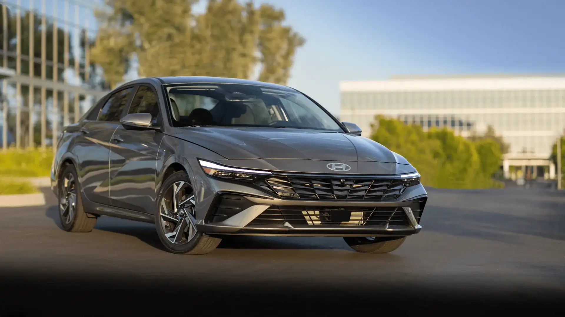 Front view of 2025 Hyundai Elantra parked near a modern building showing grille design and LED lighting.
