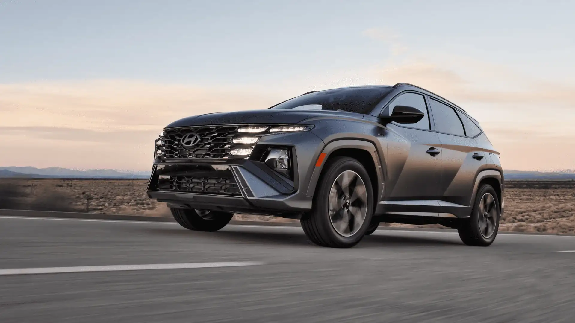 Low front view of the 2025 Hyundai Tucson in motion, highlighting black grille and multi-beam LED headlights.