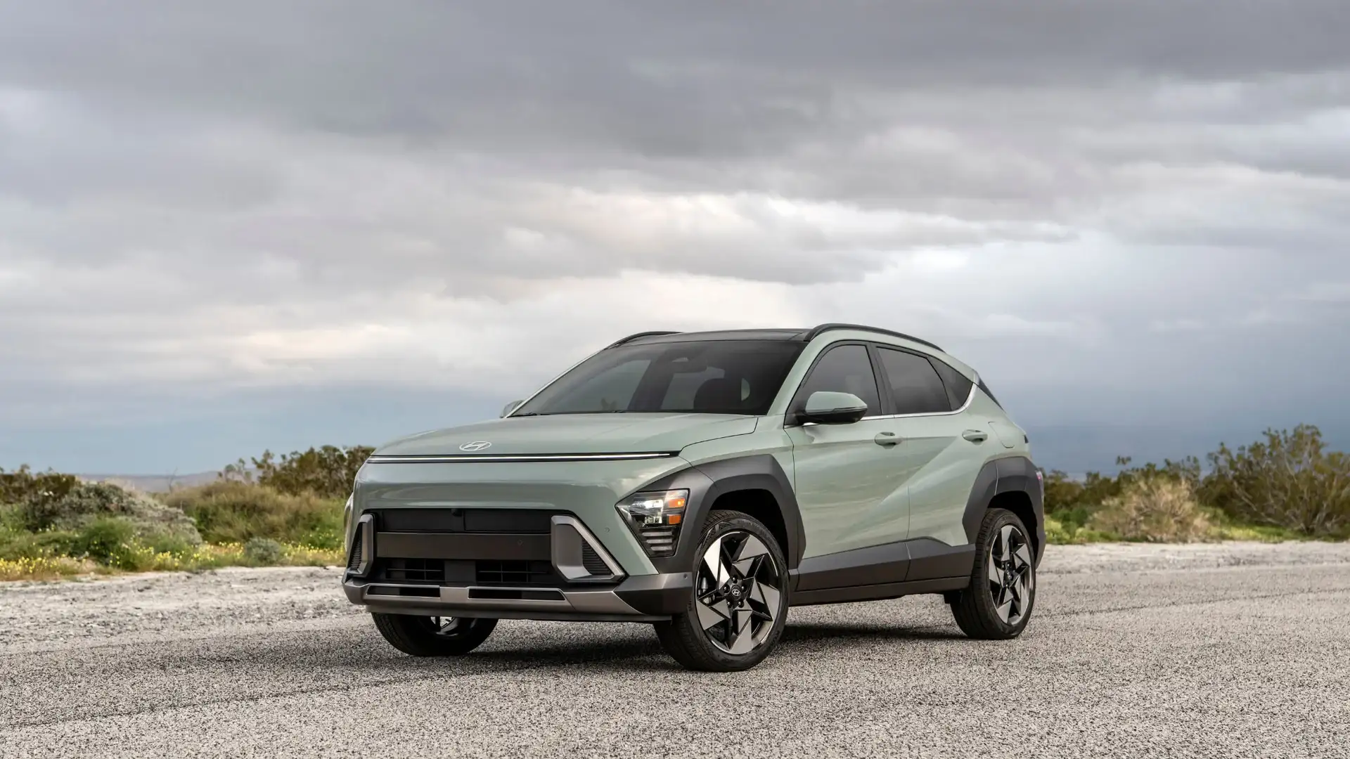 2026 Hyundai Kona SUV in sage green set against mountain backdrop, highlighting bold front fascia, wide grille, and distinctive LED lighting.
