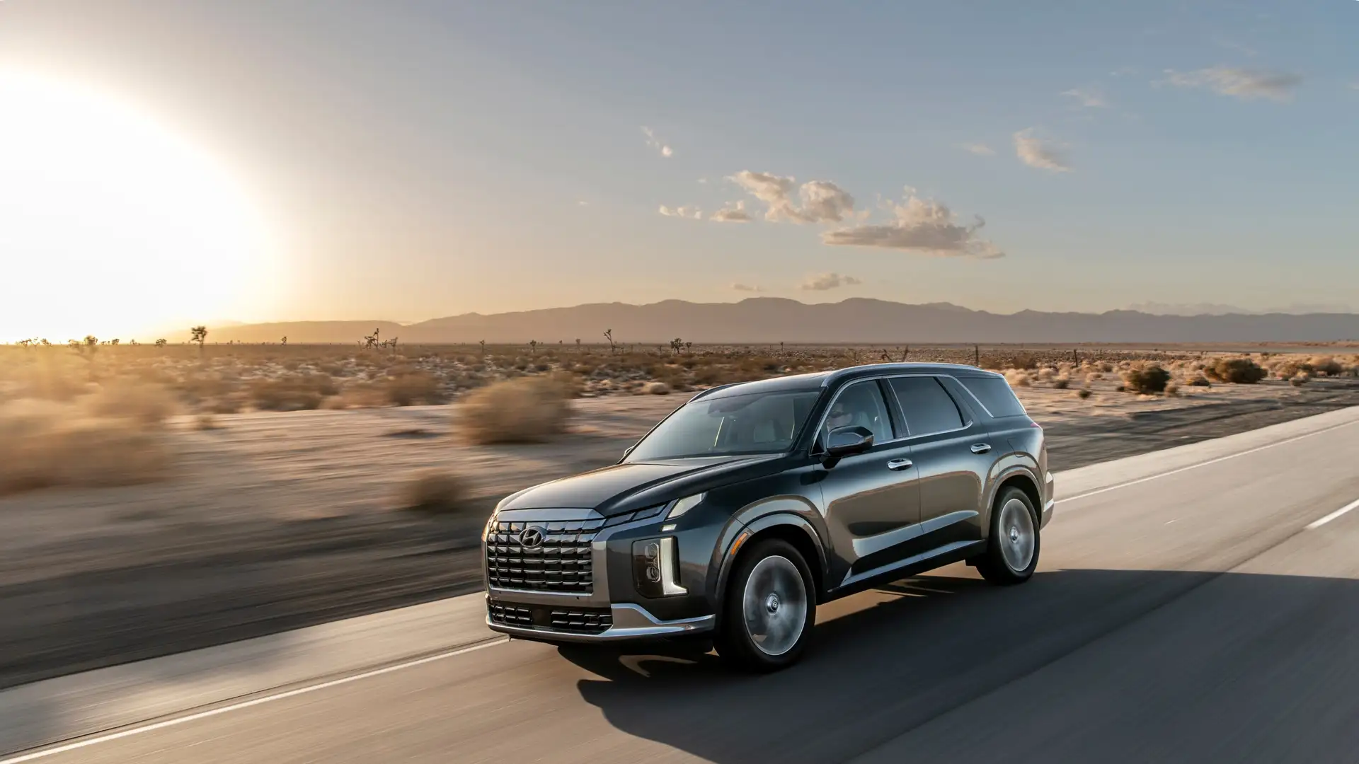 2025 Hyundai Palisade luxury SUV driving through the desert highway at sunset highlighting premium styling and comfort.