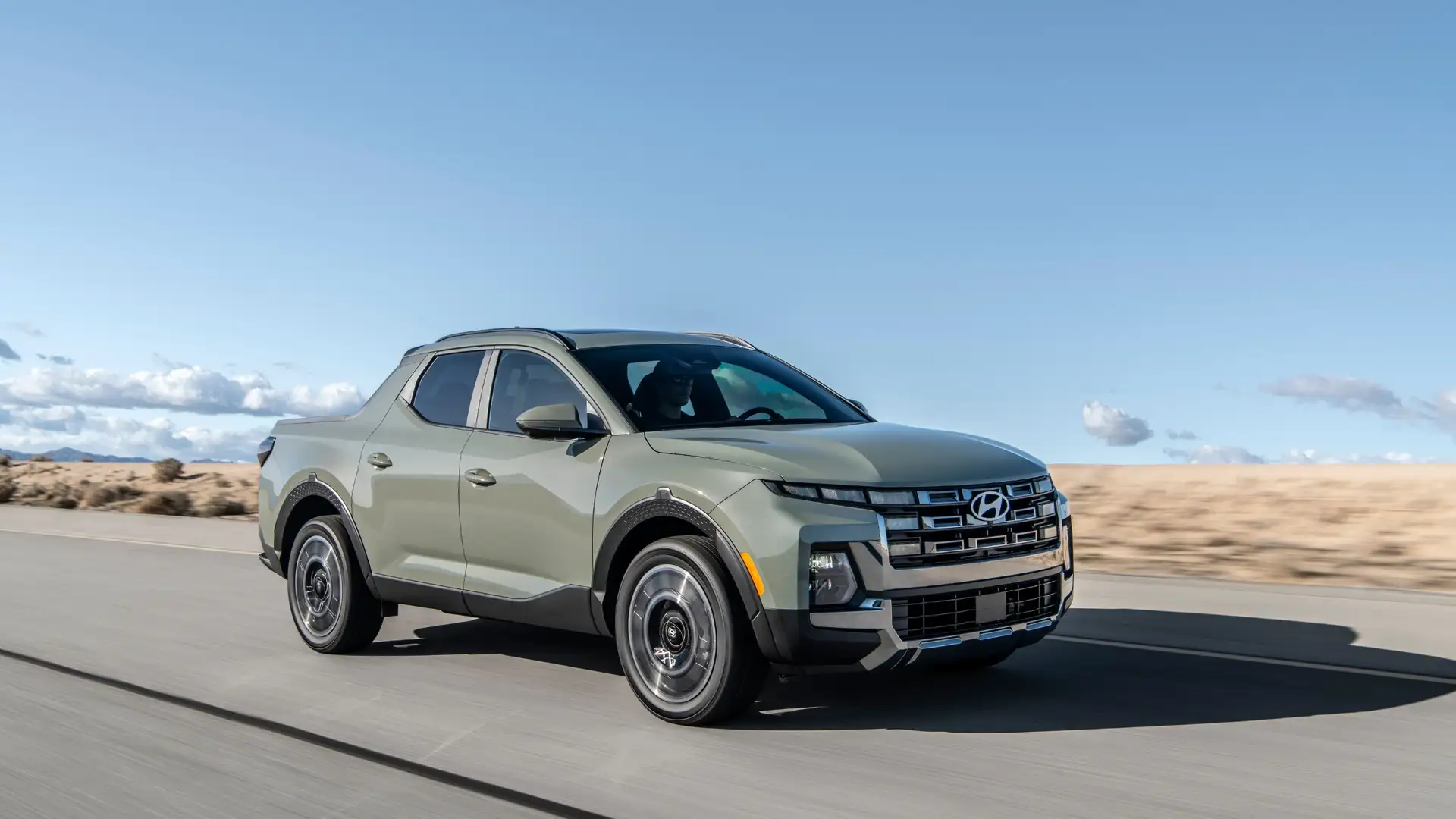 2025 Hyundai Santa Cruz driving on open road with rugged stance and signature grille design.