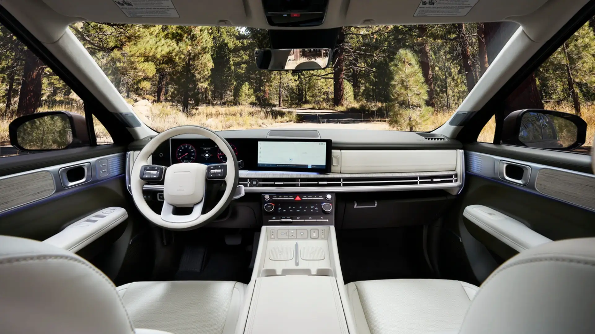 2026 Hyundai Santa Fe Hybrid interior with white leather seats, digital displays, and panoramic forest view.