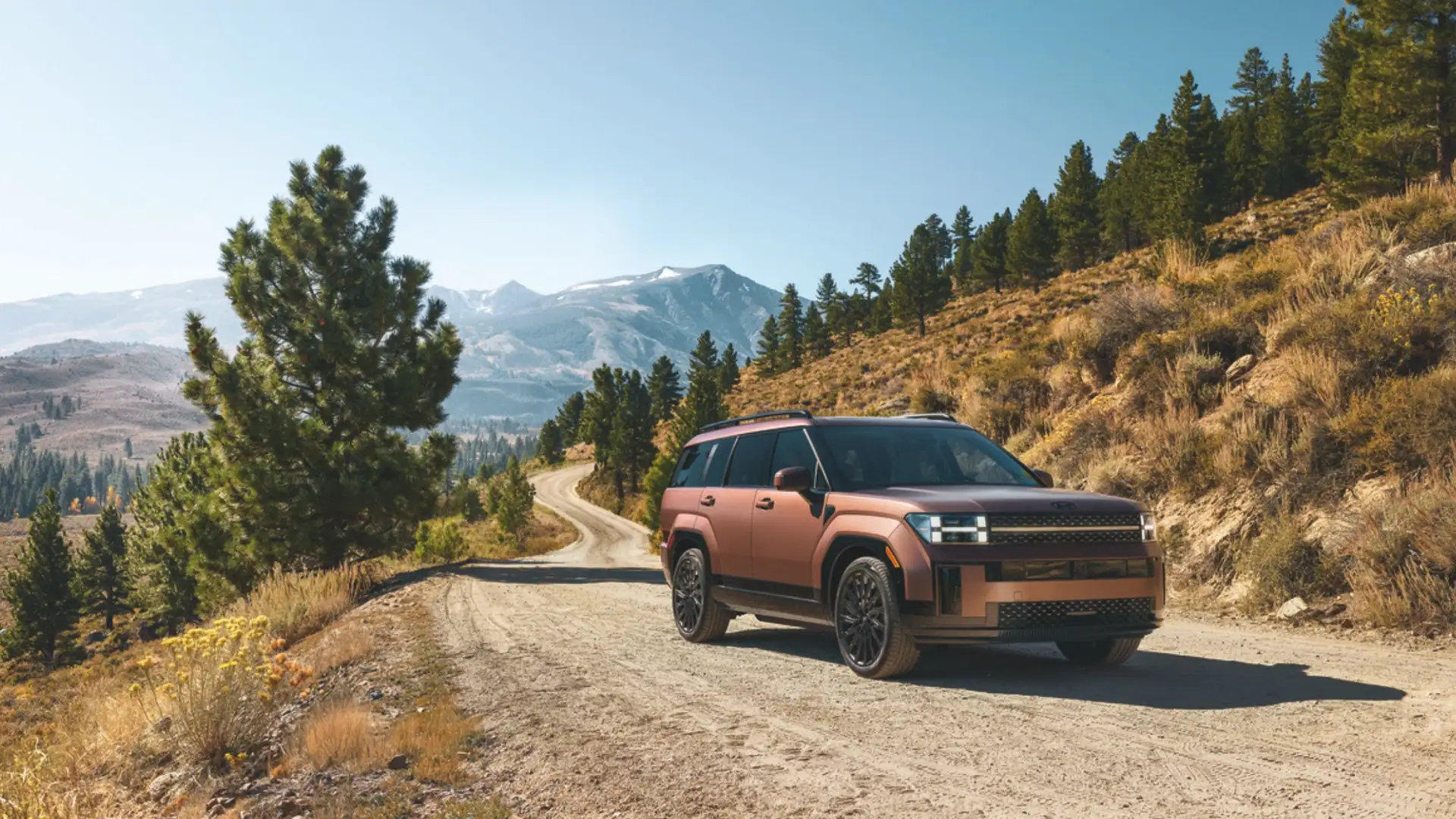 2026 Hyundai Santa Fe Hybrid on scenic dirt road with copper exterior and boxy SUV styling.